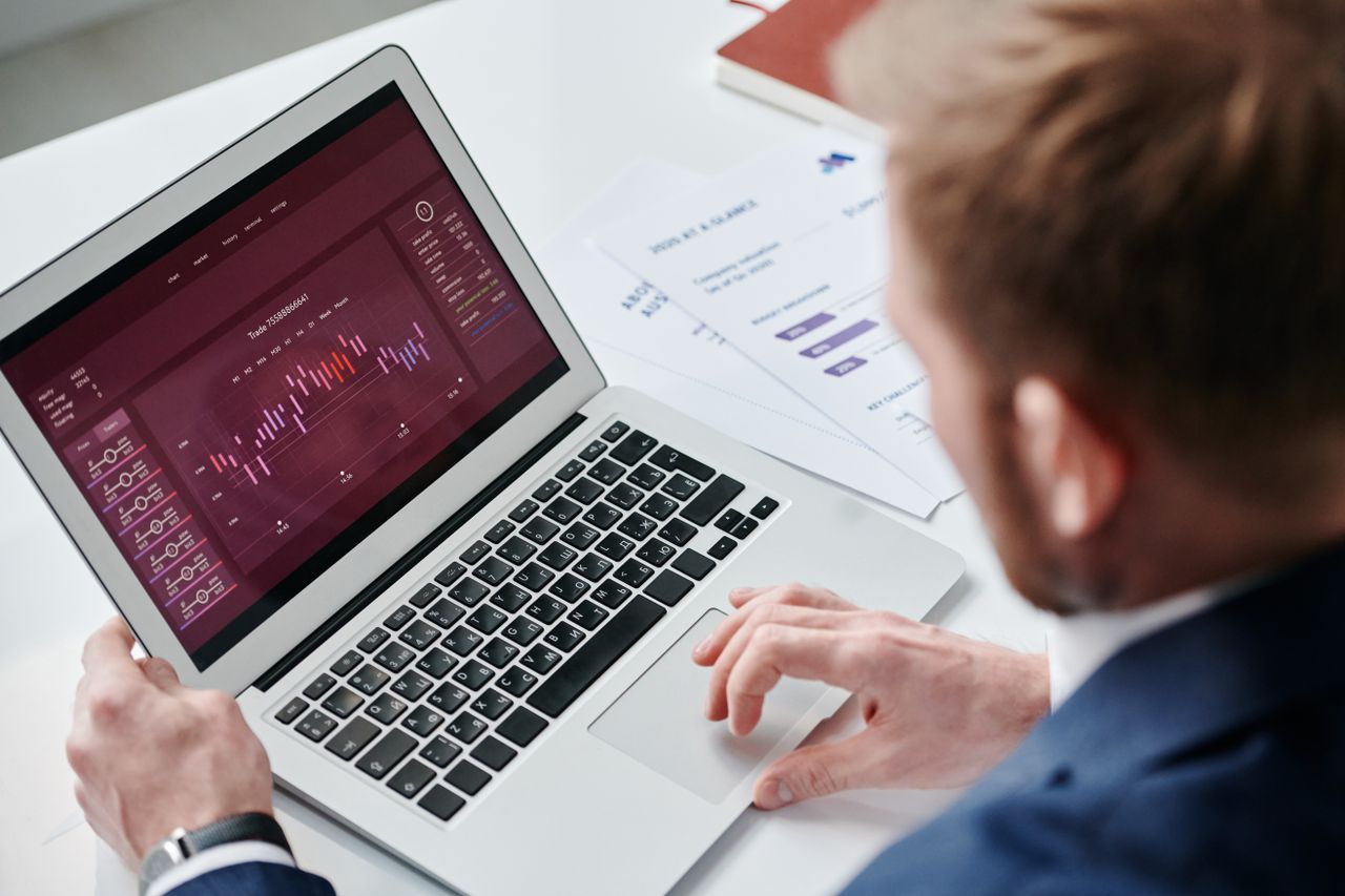 The Art of Drawing Readers In: Your attractive post title goes here Businessman reviewing data analytics dashboard on laptop in bright office.